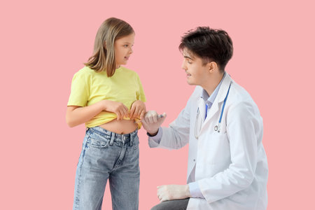Diabetic girl with doctor using lancet pen on pink backgroundの写真素材