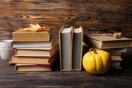 Books with autumn leaf, pumpkin and eyeglasses on wooden backgroundの写真素材