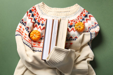 Composition with books, stylish sweater and pumpkins on green backgroundの写真素材