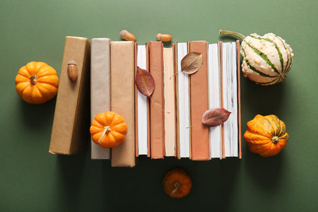 Composition with different books, pumpkins and fallen leaves on green backgroundの写真素材