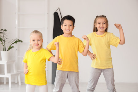 Cute little children showing muscles in gymの写真素材