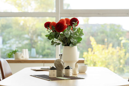 Dahlia flowers in vase and decor on dining table in room