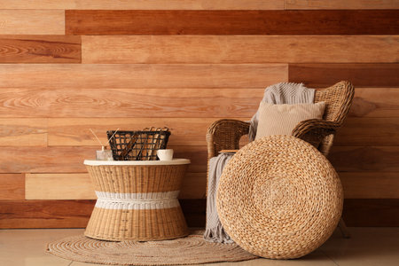 Armchair, tray with books on coffee table and pouf near wooden wall in roomの写真素材