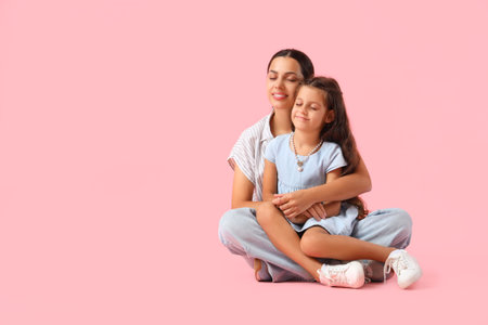 Embracing little girl with her mother sitting on pink background. International Hug Dayの写真素材