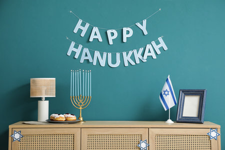 Wooden cabinet with menorah, donuts, flag of Israel and HAPPY HANUKKAH letter garland near blue wallの写真素材
