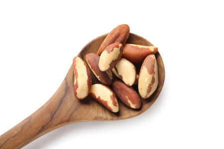 Wooden spoon with tasty Brazil nuts on white background, closeupの写真素材