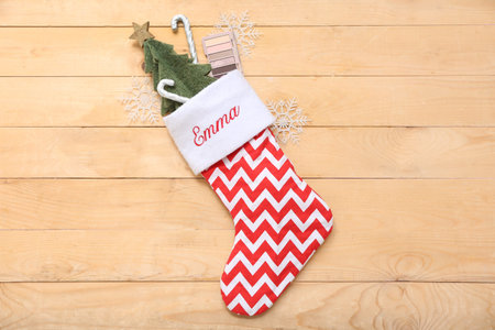 Christmas sock with eye shadow, fire tree candy canes on light wooden background. Top view