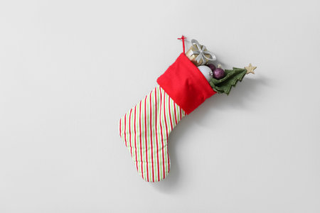 Christmas sock with gift box, mini fir tree balls hanging on white wall