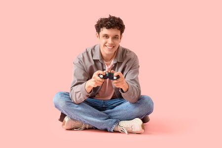 Handsome young man playing video game on pink background