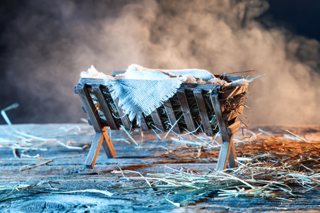 Manger with baby Jesus and hay on table against dark backgroundの写真素材