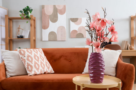 Interior of living room with sofa and magnolia flowers in vase on coffee table