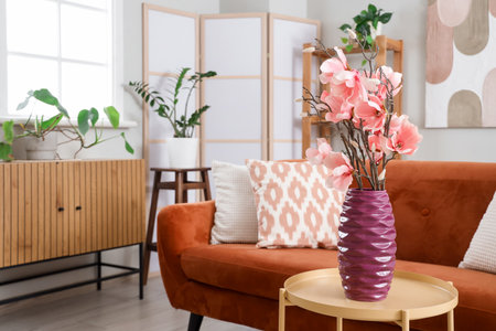 Interior of living room with sofa and magnolia flowers in vase on coffee tableの写真素材