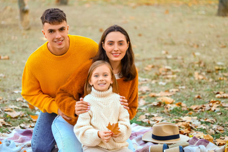Happy family sitting on picnic in beautiful autumn parkの写真素材