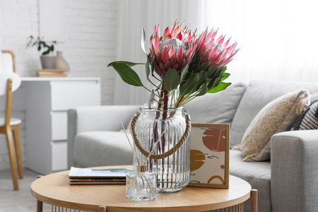 Vase with protea flowers, reed diffuser and magazines on table in living room, closeupの写真素材