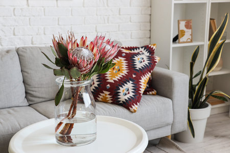 Vase with protea flowers on table in living room, closeup