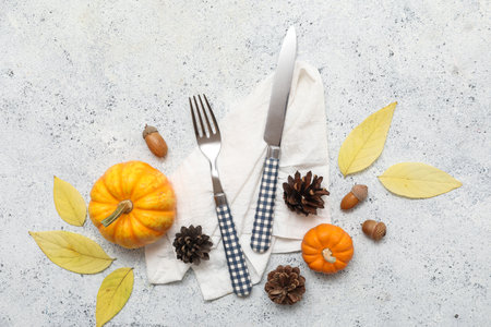 Stylish cutlery with autumn leaves, acorns, pine cones and fresh pumpkins on white backgroundの写真素材