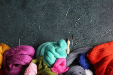Set of colorful wool for felting and needles on dark background