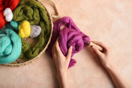 Female hands with different wool for felting and needles on color backgroundの写真素材