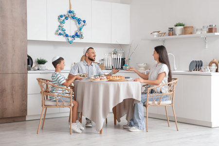 Happy family having dinner in festive kitchen with decorations for Hanukkah celebration