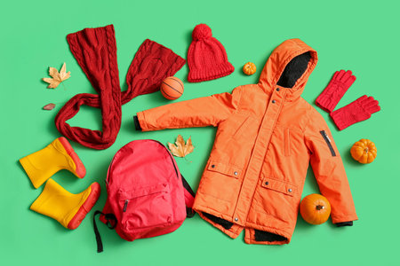 Composition with stylish children's clothes, accessories and pumpkins on green backgroundの写真素材