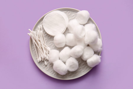 Plate with cotton balls, pads and swabs on lilac backgroundの写真素材