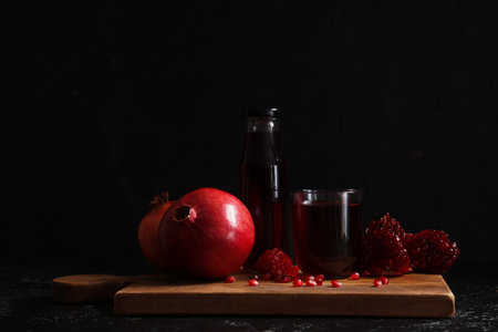 Glass and bottle of fresh pomegranate juice on black backgroundの写真素材