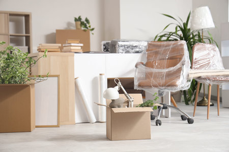 Cardboard box with things in office on moving day