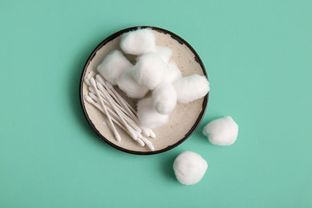 Plate with cotton balls and swabs on turquoise backgroundの写真素材