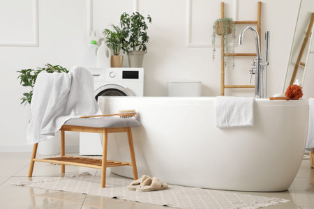 Interior of light bathroom with bathtub and gray bench