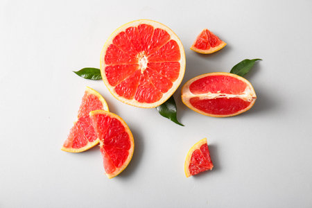 Cut fresh grapefruit and leaves on gray background