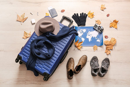Blue suitcase with shoes, world map, photo camera, passport and autumn leaves on floor. Travel conceptの写真素材
