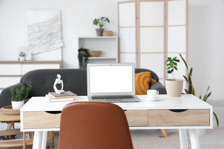 Blank laptop with coffee cup and plant on programmer's desk in living roomの写真素材