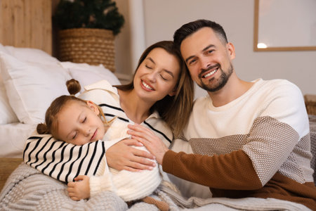 Happy parents and their little daughter sleeping in winter evening at homeの写真素材
