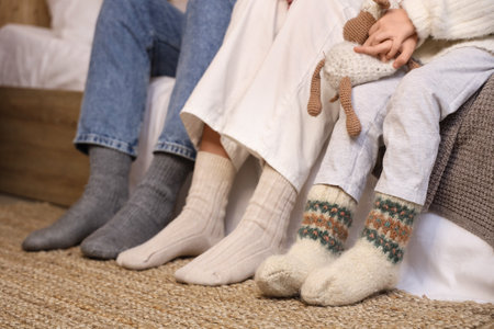 Parents and their little daughters in warm socks at home, closeupの写真素材