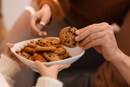 Parents and their little daughters with plate of cookies in winter day at home, closeupの写真素材