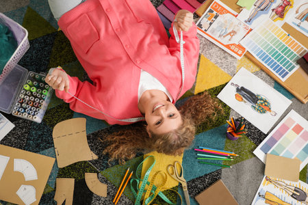 Female fashion designer with supplies lying on carpet in studio, top viewの写真素材