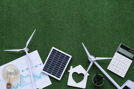Wind turbines with solar panel, house figure and light bulb on grass. Green Energy conceptの写真素材