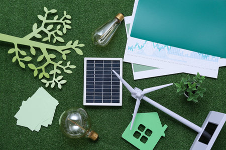 Wind turbine with solar panel, light bulbs and house figure on grass. Green Energy conceptの写真素材