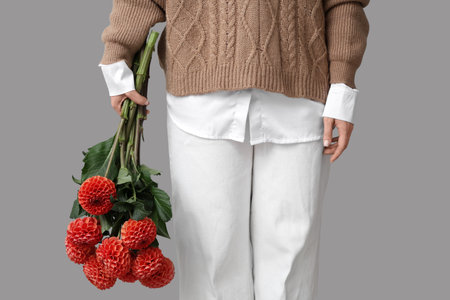 Woman with bouquet of beautiful orange dahlia flowers on gray background, closeupの写真素材