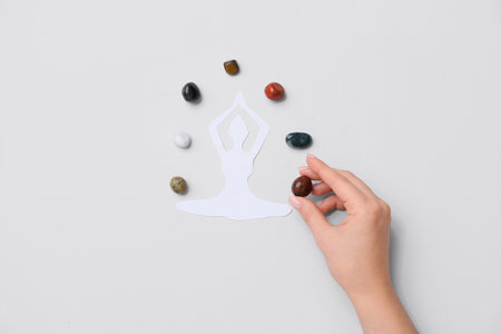 Woman with set of chakra stones and paper female figure on light backgroundの写真素材
