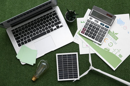 Laptop with solar panel, wind turbine, light bulb and calculator on grass. Green Energy conceptの写真素材