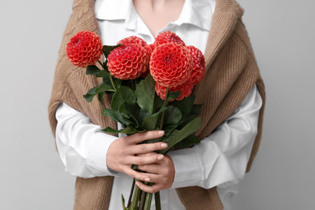 Woman with bouquet of beautiful orange dahlia flowers on gray background, closeupの写真素材