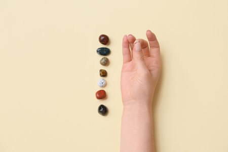 Meditating woman with set of chakra stones on yellow background