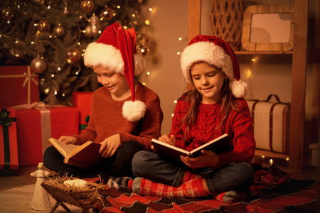Little children reading Christmas story at home in eveningの写真素材
