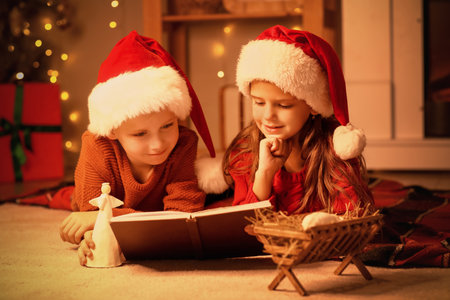 Little children reading Christmas story at home in eveningの写真素材