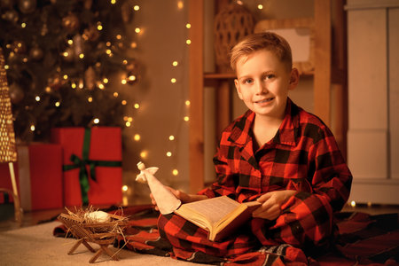 Little boy reading Christmas story at home in eveningの写真素材