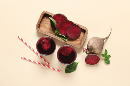 Glasses of fresh beet juice with basil and vegetables on beige backgroundの写真素材
