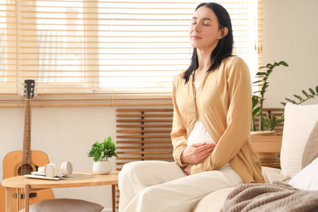Young pregnant woman sitting on couch at homeの写真素材