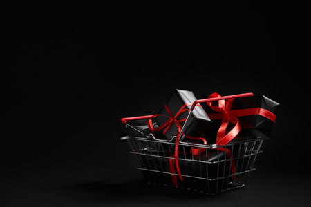 Shopping basket with gift boxes on dark background. Black Friday saleの写真素材