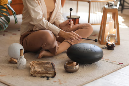 Young woman with sticks playing glucophone on carpet at home